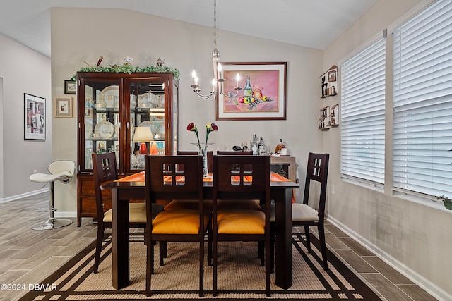 dining area with hardwood / wood-style floors, a chandelier, plenty of natural light, and vaulted ceiling