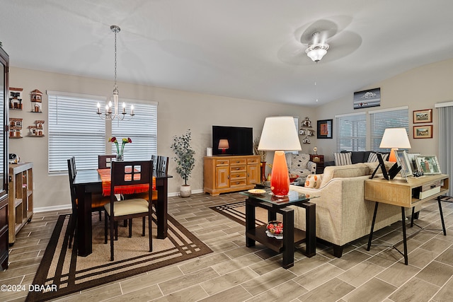 living room featuring ceiling fan with notable chandelier and vaulted ceiling