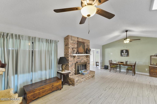 living room featuring a fireplace, ceiling fan, and lofted ceiling