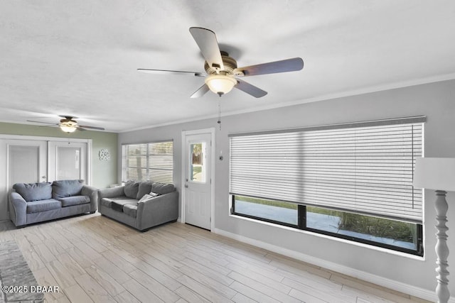 living room featuring ceiling fan, light wood-type flooring, and ornamental molding