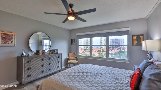 bedroom featuring light hardwood / wood-style floors, multiple windows, a textured ceiling, and ceiling fan