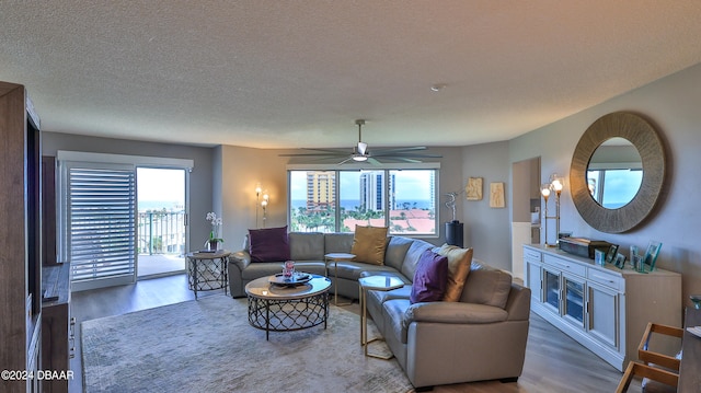 living room featuring wood-type flooring, ceiling fan, and a textured ceiling