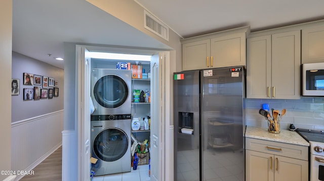 washroom with stacked washer / drying machine and light wood-type flooring