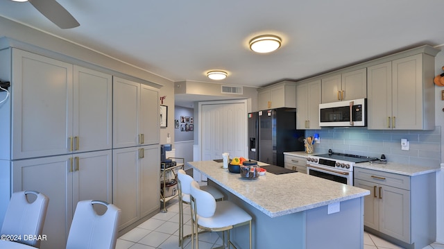 kitchen with gray cabinets, stainless steel stove, black fridge with ice dispenser, and light tile patterned floors