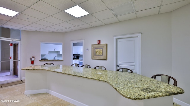 kitchen featuring white cabinetry, a drop ceiling, and light tile patterned floors