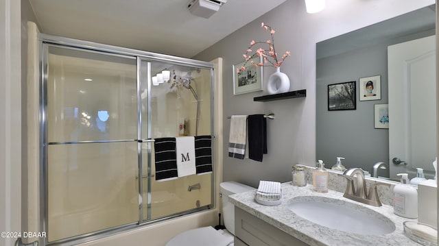 full bathroom with combined bath / shower with glass door, vanity, and toilet