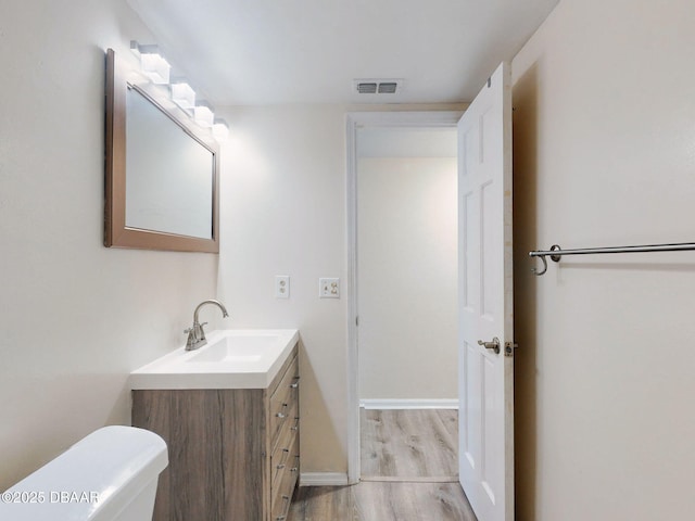 bathroom with vanity, toilet, and hardwood / wood-style floors