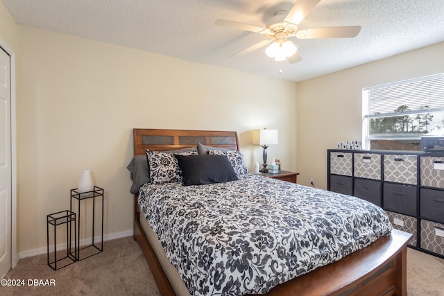 carpeted bedroom featuring ceiling fan and a textured ceiling