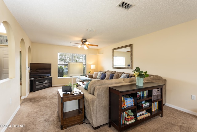 living room with ceiling fan, a textured ceiling, and light carpet