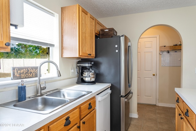 kitchen with dishwasher, a textured ceiling, tile patterned floors, and sink