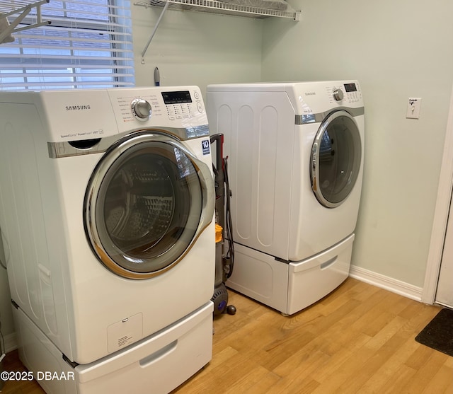 laundry area featuring light wood-type flooring, baseboards, washing machine and dryer, and laundry area