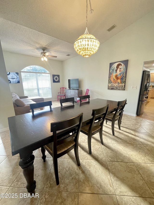 dining room with visible vents, ceiling fan with notable chandelier, a textured ceiling, baseboards, and vaulted ceiling