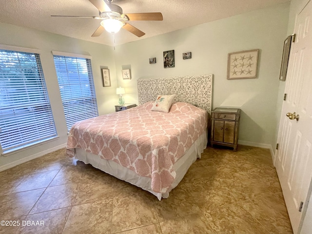 bedroom with a ceiling fan, baseboards, and a textured ceiling