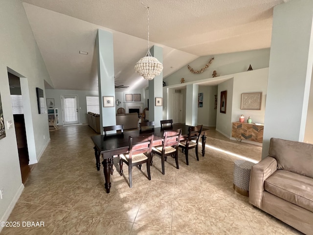 dining room with vaulted ceiling, ceiling fan with notable chandelier, baseboards, and a textured ceiling