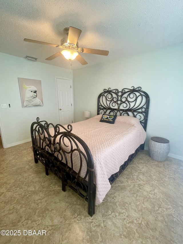 bedroom featuring baseboards, a ceiling fan, visible vents, and a textured ceiling