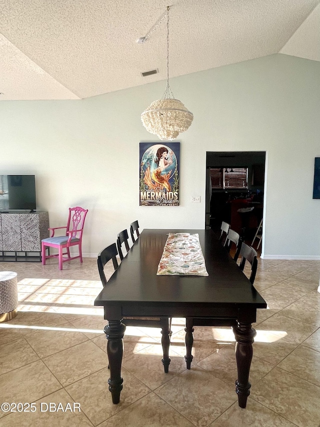 tiled dining area with visible vents, a textured ceiling, baseboards, and vaulted ceiling