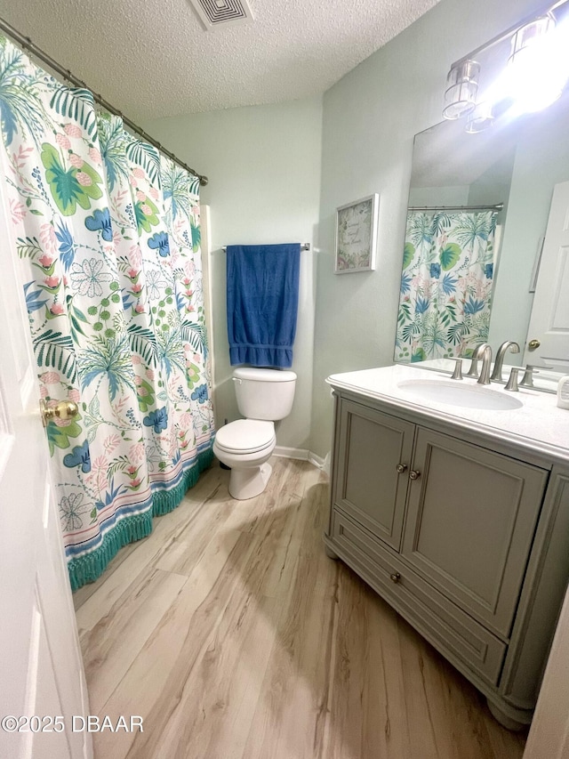 full bathroom featuring vanity, a shower with shower curtain, wood finished floors, a textured ceiling, and toilet