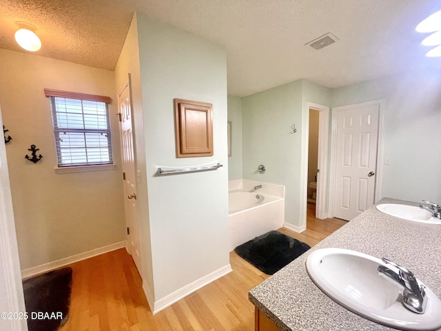 full bathroom featuring a sink, visible vents, a textured ceiling, and wood finished floors