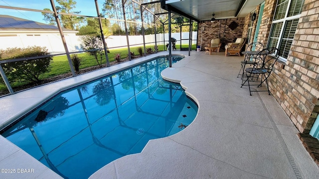 view of swimming pool with a fenced in pool, glass enclosure, a fenced backyard, a patio area, and a ceiling fan