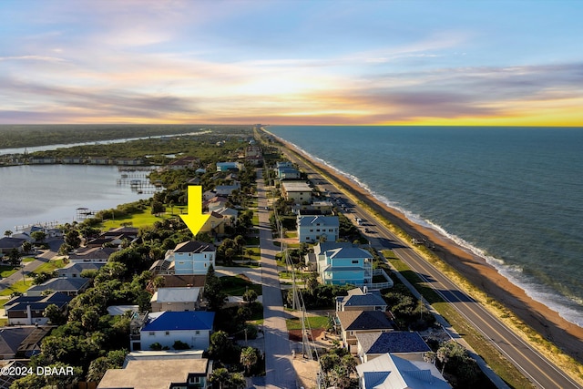 aerial view at dusk featuring a water view and a view of the beach