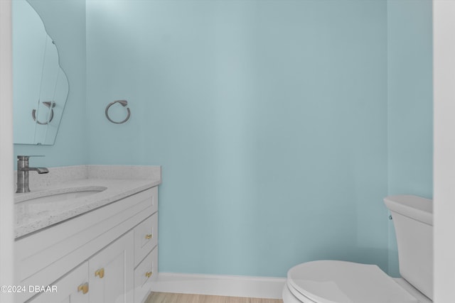 bathroom with toilet, vanity, and hardwood / wood-style floors