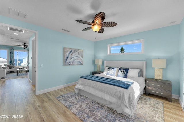 bedroom featuring ceiling fan, multiple windows, and light hardwood / wood-style floors