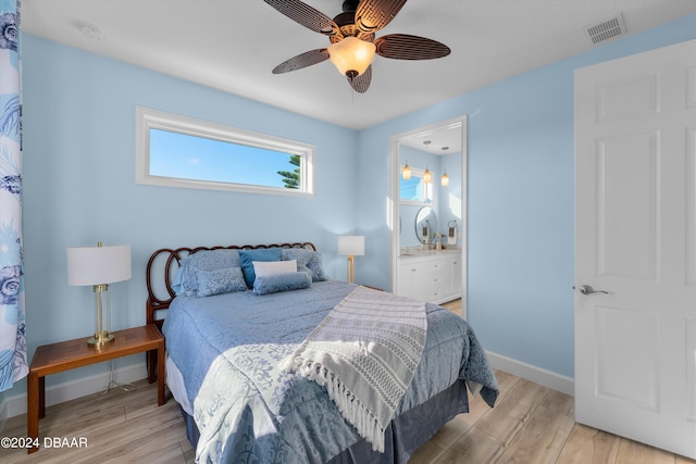 bedroom with light wood-type flooring, ensuite bath, and ceiling fan