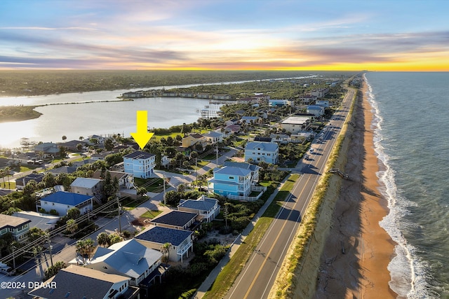 aerial view at dusk with a view of the beach and a water view