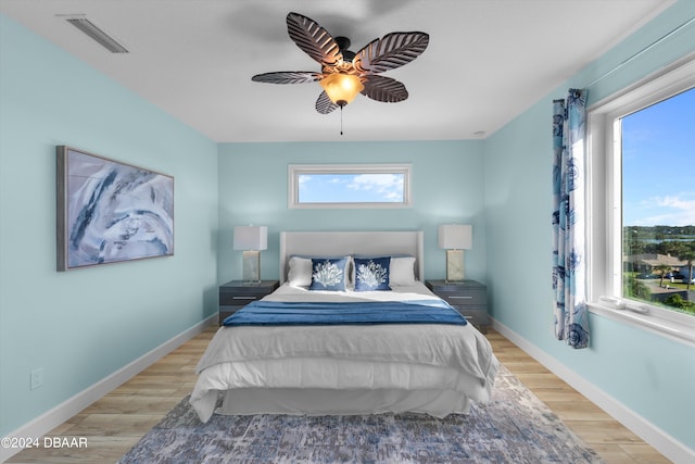 bedroom with light wood-type flooring, multiple windows, and ceiling fan