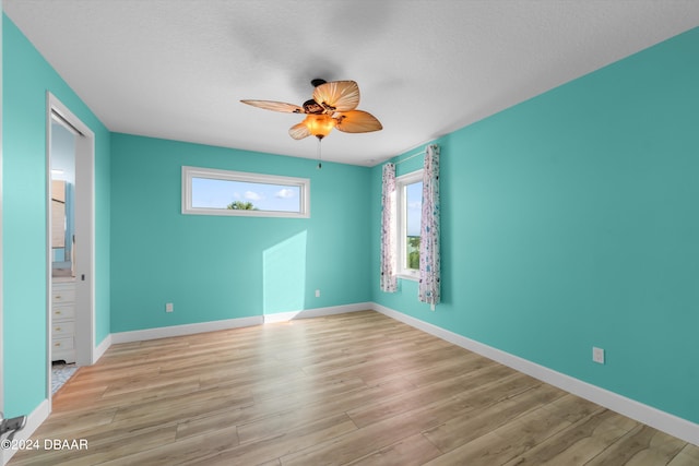 unfurnished room with a textured ceiling, light wood-type flooring, and ceiling fan