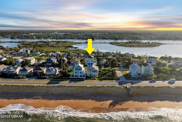 aerial view at dusk with a view of the beach and a water view