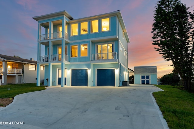 view of front facade with a garage, central air condition unit, a lawn, and a balcony