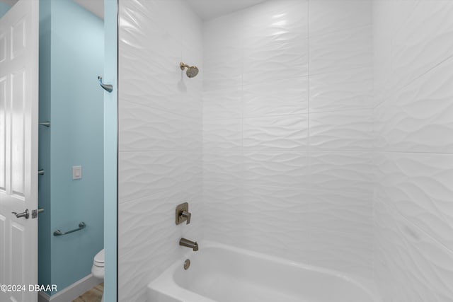 bathroom with toilet and tiled shower / bath