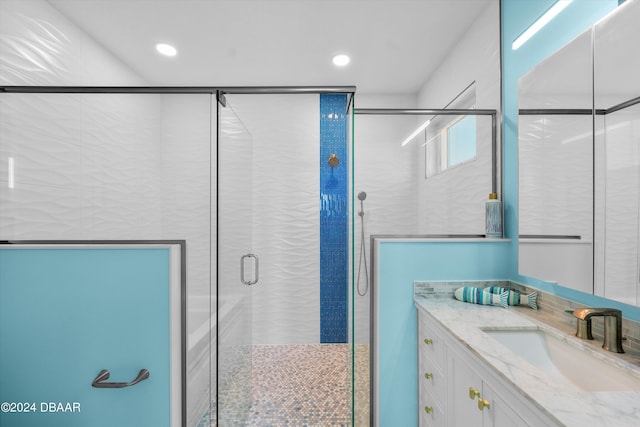 bathroom featuring a shower with shower door and vanity