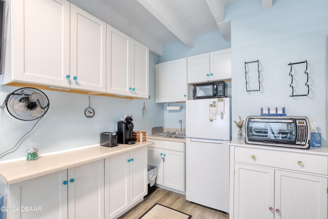 kitchen featuring light hardwood / wood-style floors, white refrigerator, white cabinetry, and a textured ceiling