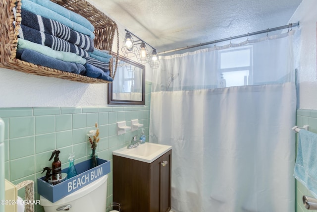 bathroom featuring a textured ceiling, curtained shower, vanity, and tile walls