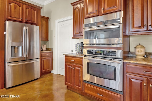 kitchen with light tile patterned flooring, light stone counters, crown molding, and appliances with stainless steel finishes