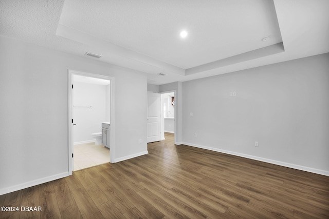 empty room featuring hardwood / wood-style flooring, a textured ceiling, and a tray ceiling