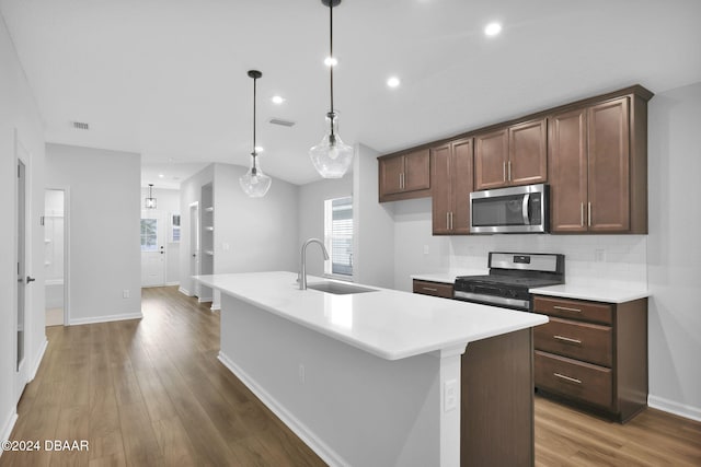 kitchen featuring sink, stainless steel appliances, dark hardwood / wood-style floors, an island with sink, and decorative light fixtures