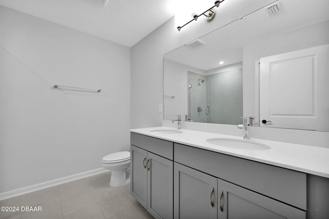 bathroom featuring vanity, a shower with door, tile patterned floors, toilet, and a textured ceiling