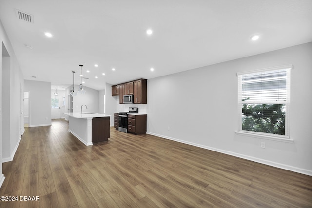 kitchen featuring decorative light fixtures, a kitchen island with sink, dark wood-type flooring, and appliances with stainless steel finishes