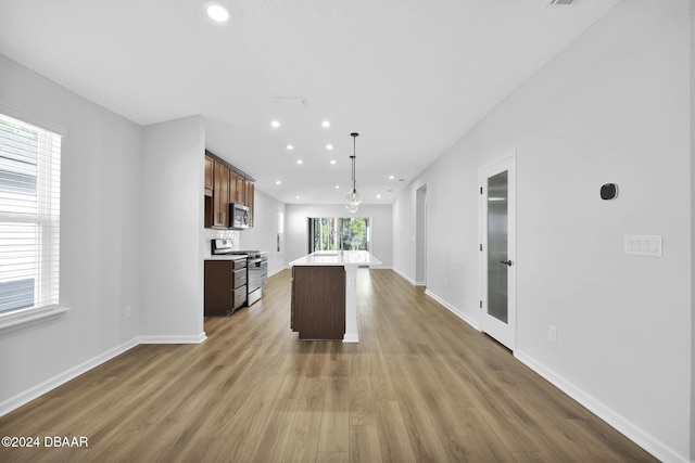 kitchen featuring hardwood / wood-style floors, pendant lighting, a kitchen island, and stainless steel appliances