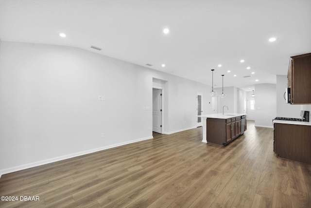 kitchen featuring a kitchen island with sink, dark brown cabinets, pendant lighting, and dark hardwood / wood-style floors