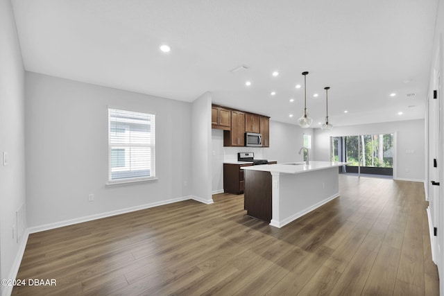 kitchen with stainless steel appliances, plenty of natural light, a center island with sink, and dark hardwood / wood-style floors