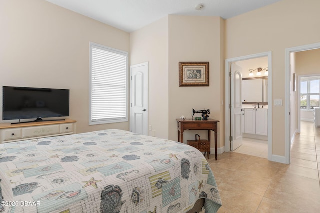 bedroom with a sink, light tile patterned floors, baseboards, and ensuite bath