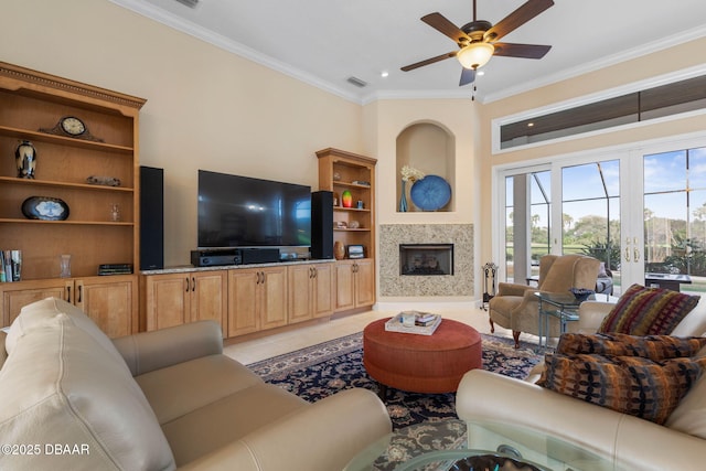 living area with crown molding, ceiling fan, light tile patterned floors, a glass covered fireplace, and visible vents