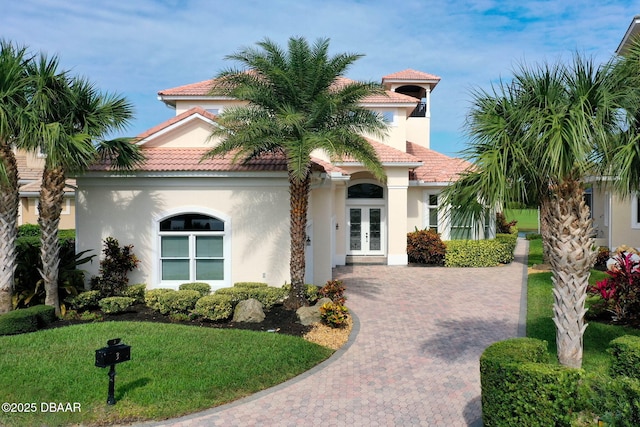 mediterranean / spanish house featuring french doors, a tile roof, and stucco siding