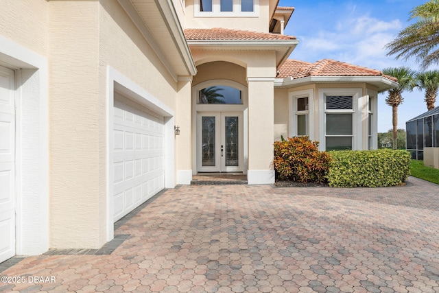 doorway to property with french doors, stucco siding, a tile roof, and decorative driveway