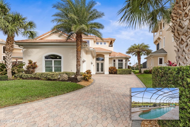 mediterranean / spanish-style house with french doors, decorative driveway, stucco siding, and a tile roof