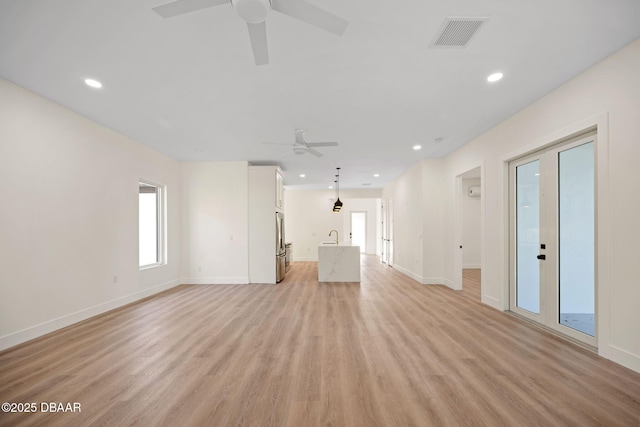 unfurnished living room with sink, light hardwood / wood-style floors, and ceiling fan